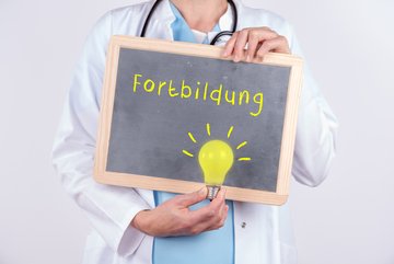 Foto Arzt hält Schiefertafel mit der Aufschrift Fortbildung